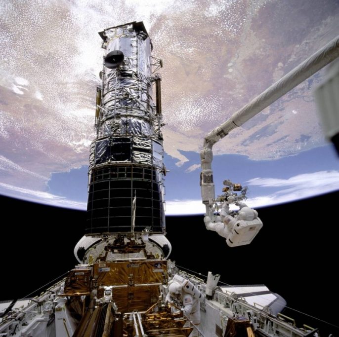 Former NASA astronaut Story Musgrave anchored to a robotic arm during one of his many space walks to make repairs and upgrades to the Hubble Space Telescope. (Photo credit: NASA)